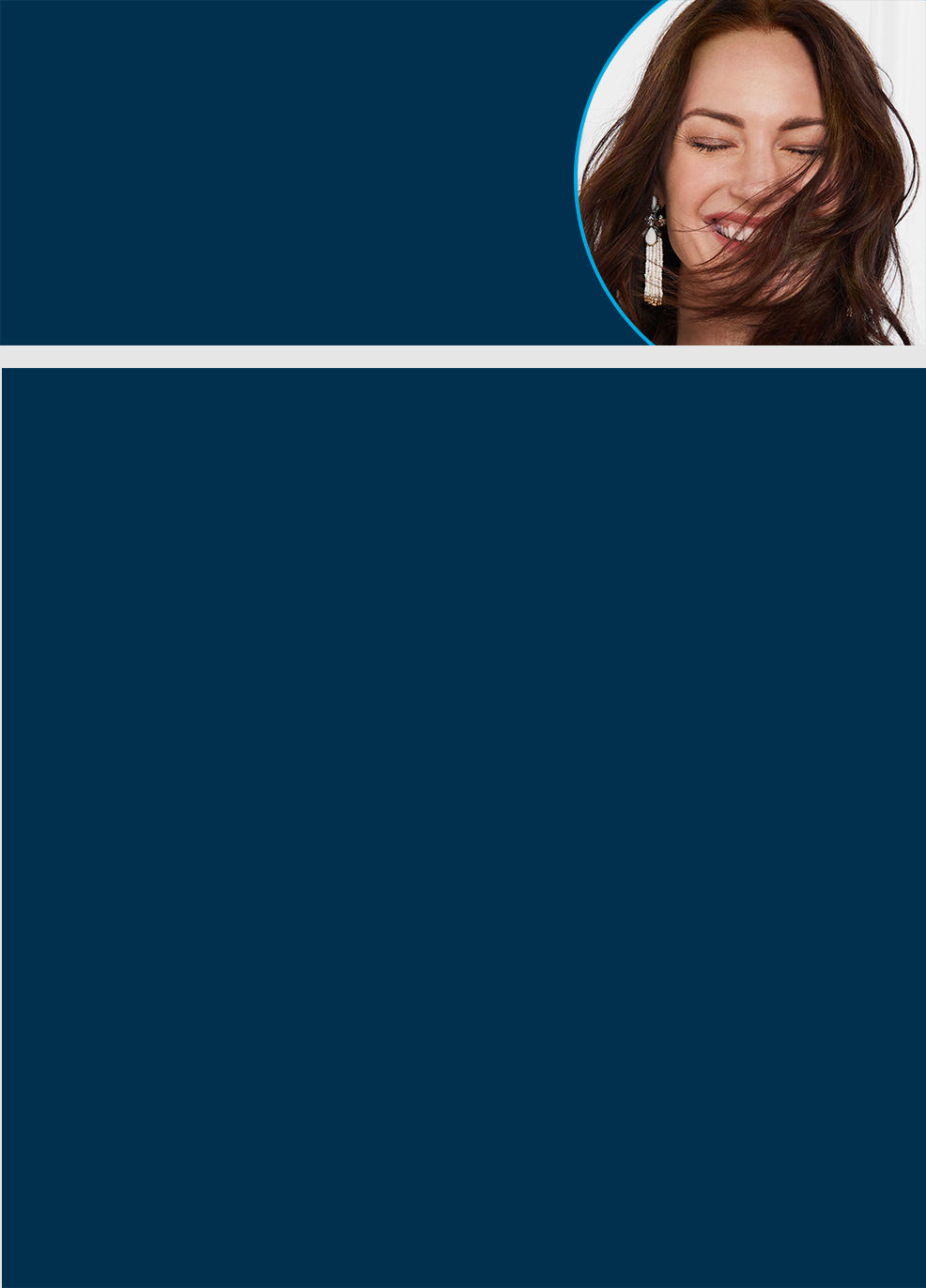 a woman smiles with her eyes closed and some of her hair in her face